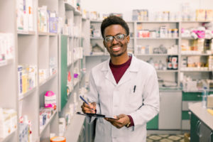 Pharmacy technician holding clipboard in pharmacy.