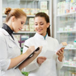 Pharmacy technician assisting pharmacist with tasks in a pharmacy.