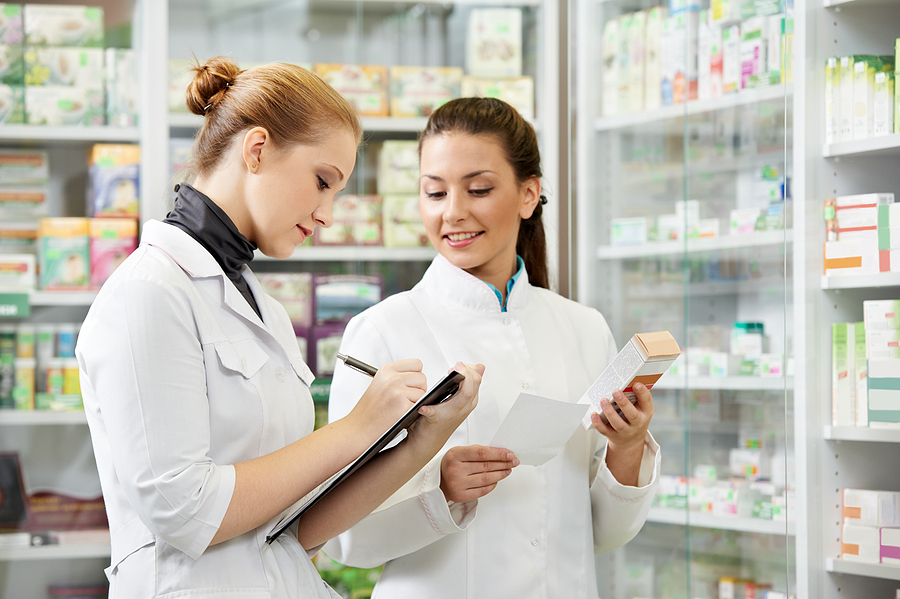 Pharmacy technician assisting pharmacist with tasks in a pharmacy.